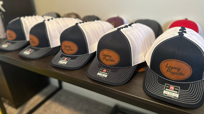 Row of baseball caps with leather patches on a wooden surface.
